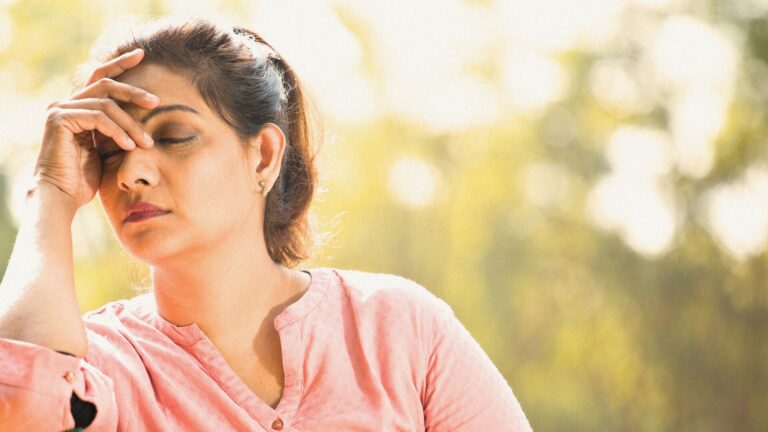 Woman wearing pink shirt holding head in hand