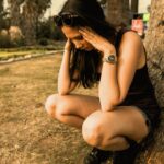 photo of a woman crouching while her hands are on her head