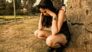 photo of a woman crouching while her hands are on her head